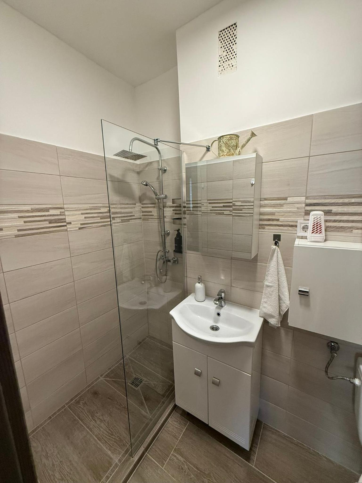 Boulevard Apartman – Fürdőszoba üvegfalas zuhanyzóval és mosdóval